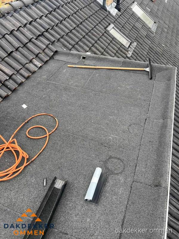 Plat dak reparatie met gereedschap en loodstroken in Ommen